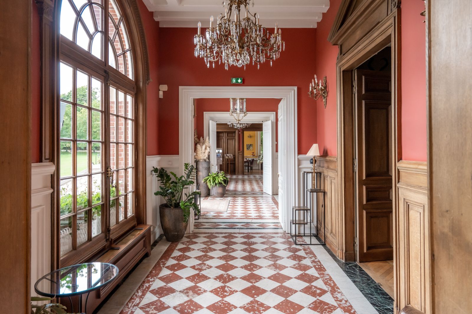 Mariage baroque dans un château en Normandie. Couloir majestueux, tons terracota, bois , vue dégagée sur le parc.